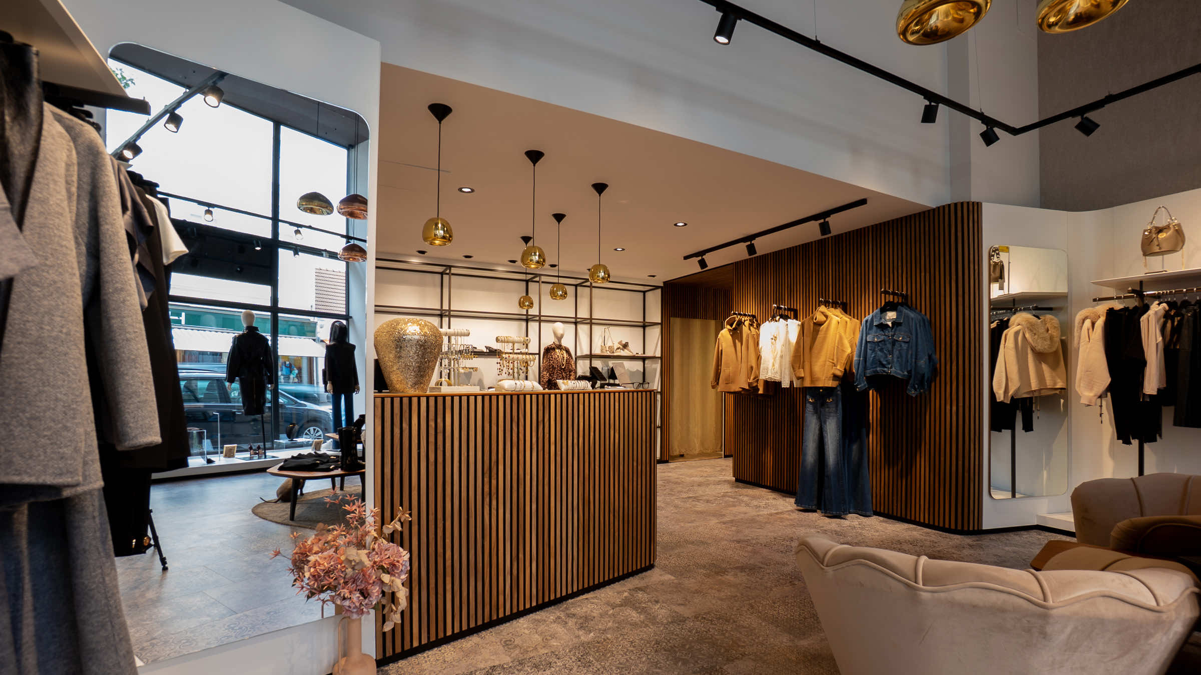Blick durch die LIMAA Boutique in Baden zur Schaufensterfront mit Tageslicht, Holztresen mit Schmuck und einem hellen Samtsessel im Vordergrund